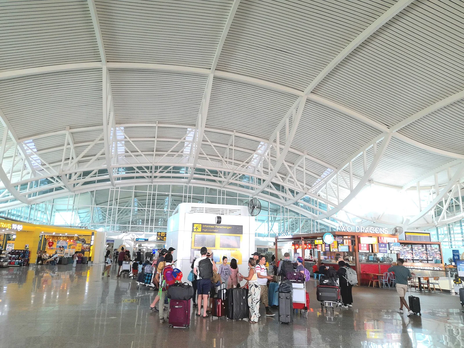 The terminal at Bali's international airport near Denpasar, with travellers pushing luggage trolleys under a wide roof